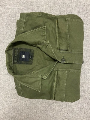 Grön overshirt från G-Star RAW - Säljer en grön overshirt från G-Star RAW med fickor framtill och klassisk krage. Jackan har knäppning med knappar och är tillverkad i slitstark bomull. Overshirten är i storlek XL, köpt på Best of Brands Sickla för ca 1100kr och använd ca 2ggr. Hör gärna av er vid frågor. Mvh Olof 