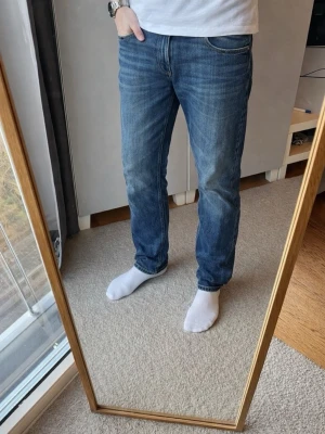 Blå jeans från Replay - Snygga blå jeans från Replay med klassisk femficksdesign och gylf. Perfekta för en avslappnad stil. Märkesdetaljer på baksidan ger en extra touch. Bra skick, inga defekter. Säljs nu för endast 269kr!