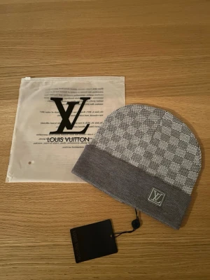 mössa - Snygg grå mössa  med klassiskt rutigt mönster och uppvikt kant. Mössan har en diskret logga framtill och kommer med originalpåse och tagg. Perfekt accessoar för att lyfta din stil.