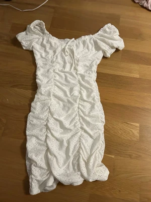 Vit kort klänning  - Supersöt vit kort klänning från H&M Divided i storlek XS. Klänningen har broderade detaljer och den stretchar ut sig när man har på sig den. Tillverkad i bomull med ett luftigt och fräscht uttryck, perfekt för varma dagar. Säljes då den inte längre kommer till användning.