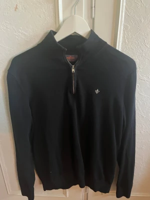 Svart half zip tröja från Morris - Svart långärmad tröja från Morris i storlek S, tillverkad av 100% pima bomull. Tröjan har en stilren half zip-dragkedja framtill och en liten broderad logga på bröstet. Perfekt för dig som gillar klassisk och enkel stil.
