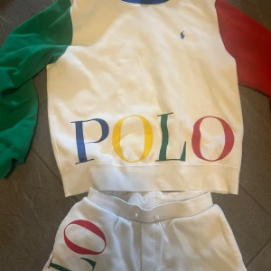 Special edition set från Ralph Lauren säljs inte längre‼️ - Säljer en vit hoodie från Polo Ralph Lauren med blå huva, gröna och röda ärmar samt stort färgglatt POLO-tryck framtill. Klassisk logga broderad på bröstet. Tröjan är i mjuk bomull och har en relaxed vibe, perfekt för dig som gillar streetstyle. OBS! Special edition säljs ej längre av Ralph lauren.