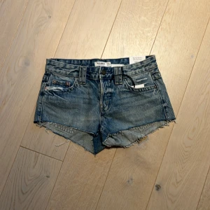 Blå jeansshorts från Pull&Bear - Säljer ett par supersnygga lågmidjade jeansshorts från Pull&Bear. De är helt oanvända och var prislappen kvar. De är i storlek 34. 