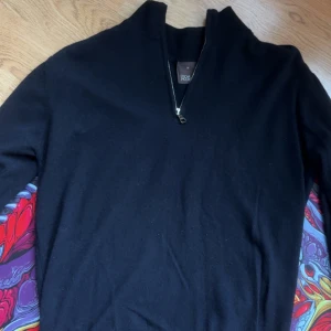 Navy kashmir-tröja Oscar Jacobson - Marinblå stickad  tröja från Oscar Jacobson med halv dragkedja och hög krage. Tillverkad i Italien och har en klassisk, stilren look som passar perfekt till lager-på-lager. Materialet är mjukt och ger en exklusiv känsla. Tröjan är i det dyra tyget kashmir, Nypris 1700, mitt pris 1050