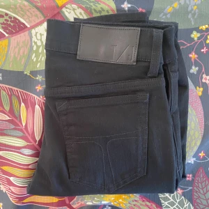 Tiger of Sweden Jeans - Snygga svarta skinny jeans från Tiger of Sweden med klassisk femficksdesign och diskret logotyp på bakfickan. Jeansen har smal passform och är tillverkade i ett mjukt bomullsmaterial med lite stretch för extra komfort. Perfekta för en clean och stilren look.