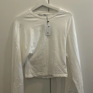 Vit långärmad tröja från H&M - En basic vit långärmad tröja från H&M i mjuk bomull. Enkel och clean design med rund halsringning, perfekt att styla med jeans eller kjol. Skön passform och passar till många olika looks.sitter lite tajtare i midjan 