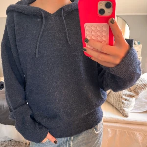 Hoodie - Mysig mörkblå stickad hoodie med huva och snörning. Tröjan har lång ärm och en relaxed, lite loose passform. Perfekt för kyliga dagar och enkel att matcha med jeans eller mjukisbyxor.