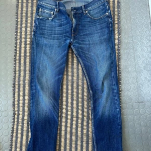 Blå jeans från Stone Island med patch - Stone Island jeans i storlek W30 L32. Jeansen är i bra skick men har dock 2 slitningar (bild 4/5). Jeansen är snygga och sticker ut bland mängden. Pris 700.