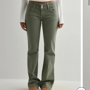 Gröna bootcut jeans med broderade fickor - Snygga gröna jeans med bootcut-modell och låg midja. Byxorna har klassiska fem fickor och coola broderade detaljer på bakfickorna. Stängs med dubbla knappar och dragkedja. Perfekta för dig som gillar en avslappnad men trendig stil.