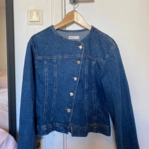 Jeansjacka  - Snygg jeansjacka i klassisk blå färg. Jackan har en unik asymmetrisk knäppning med silverfärgade knappar och raka sömmar som ger en cool look. Rund halsringning och långa ärmar. Perfekt för dig som vill sticka ut lite extra.  Den är helt ny och pris går att diskutera 💖