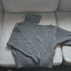 Svart stickad polotröja från Gina Tricot storlek xxs - Svart stickad polotröja från Gina Tricot i storlek XS. Tröjan har en hög polokrage och lång ärm, samt en öppning vid ena axeln. Jag är 160cm lång.