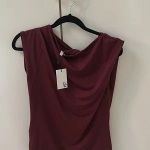 Vinröd tröja från 157 - Supersnygg vinröd klänning från 157 Tröjan är ärmlös och har en elegant.Perfekt för dig som vill sticka ut lite extra. Storlek M passar även för dig som har L. Tröjan är även helt ny och aldrig använts. pris går cok diskuteras.