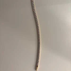 Guldigt tennisarmband från Edblad - Superfint tennisarmband från Edblad i guldton med gnistrande vita stenar längs hela bandet. Armbandet är smalt och elegant, perfekt för att ge lite extra bling till din look. Låset är diskret och armbandet kommer i original ask. Nypris 799 kr💖💖 knappt använt. 16 cm långt