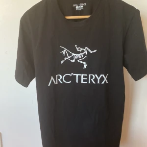 Svart Arc'teryx t-shirt med logga(nyskick) - Svart t-shirt från Arc'teryx i bomull med stor vit logga och skelettmotiv på bröstet. Klassisk passform och rund halsringning, perfekt för dig som gillar stilrena och sportiga plagg. Enkel att matcha med jeans eller shorts.