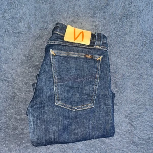 Nudie Jeans - Snygga mörkblå jeans från Nudie Jeans med klassisk femficksdesign och kontrastsömmar. Längd 102cm midja 34cm. W30 men L storleken är utnött så man ej kan se den men jag bedömer den till L32 men utgå ifrån måtten :) Ifall det inte finns någon bild i annonsen där jag bär plaggen jag säljer så är det för att jag ej kan ha storleken heller passformen, så kolla måtten för storlek och googla på modellnamnet för passform 😉 Modell super slim Kim. (Jag vet ej om det är en dam heller herr modell) 