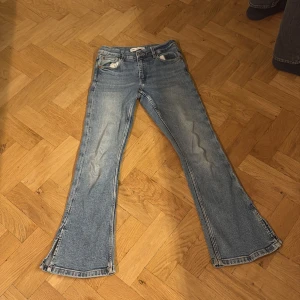 Blå bootcut jeans från Zara - Säljer ett par blå bootcut jeans från Zara i storlek 152. Jeansen har klassisk femficksdesign, normal passform upptill och vida ben med snygg utsvängning nertill. Tillverkade i jeansmaterial med ljus tvätt och slitna detaljer för en cool look.