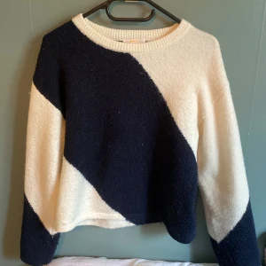 Randig stickad tröja från Gina Tricot - Säljer en stickad tröja från Gina Tricot i storlek 158/164. Tröjan har breda diagonala ränder i mörkblått och vitt, rund halsringning och långa ärmar. Perfekt för dig som gillar en mysig och stilren look.