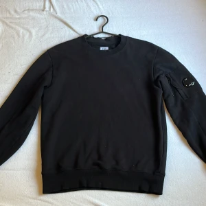 Svart sweatshirt från C.P. Company - Säljer en stilren svart sweatshirt från C.P. Company (äkta). Tröjan är i bra skick och användes sparsamt. Bara att höra av sig vid frågor! 