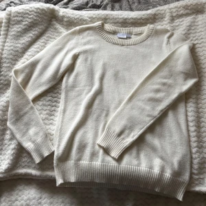 Vit stickad tröja från Vila - Klassisk vit stickad tröja från Vila med rund halsringning och ribbade muddar vid ärmslut och nederkant. Perfekt för lager-på-lager och enkel att matcha med allt. Långärmad och mjuk i materialet för en chill och stilren look.