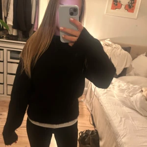 Svart stickad tröja med loose fit - Mysig svart stickad tröja med rund hals och långa ärmar. Tröjan har en loose fit och är perfekt att slänga på sig när det är kallt ute. Enkel och stilren design som funkar till allt. Snygg att styla med jeans eller leggings. Den är säven lite piffig på axlarna men inte mycket. 