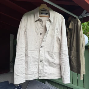 J.Lindeberg overshirt beige - Tjenare, säljer en supersnygg J.lindeberg overshirt i beige färg. Denna passar båda bra att ha som jacka och tröja. Den är i superbra skick utan tydliga deffekter, förutom en liten fläck längst ner på jackan, se bild Den är i storlek M. Hör gärna av er vid frågor och funderingar!🤗