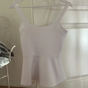 Söt vi topp från Cubus i storlek S - Supersöt vit peplumtop från Cubus storlek S. Toppen har breda axelband, figurnära överdel och en utsvängd nederdel. Perfekt att styla med jeans eller kjol. Materialet känns mjukt och har lite struktur.