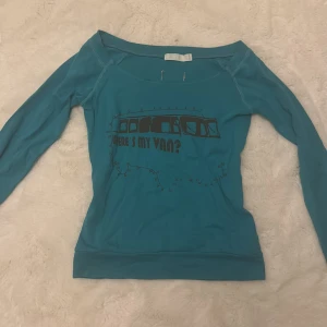 Turkos långärmad topp BY TRF - Turkos långärmad topp från BY TRF med offshoulder-skärning och tryck framtill med texten 'Where's my van?' och en tecknad van. Mjuk och stretchig i bomullsmix, perfekt för en chill och avslappnad stil.