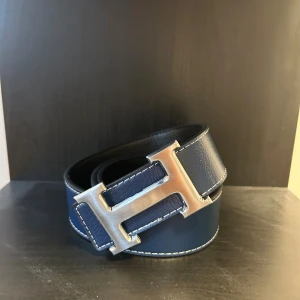 H bälte - Ett snyggt och stilrent skärp med snygg H logga! Passar perfekt nu till hösten till alla outfits. Bältet är 110cm långt och ingår även en speciell spik som man gör hål med!