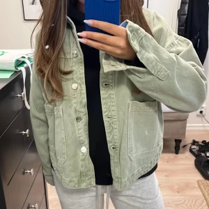 Ljusgrön jeansjacka med knappar - Säljer en ljusgrön jeansjacka från Zara  med stora fickor framtill och klassisk krage. Jackan har knäppning med silvriga knappar och en loose passform. Perfekt att slänga över en hoodie eller t-shirt. 