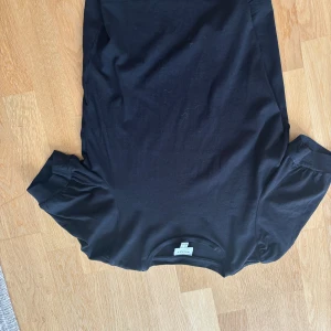 Svart t-shirt från AWARE - Svart t-shirt från AWARE by Vero Moda med rund hals och korta puffärmar. T-shirten är gjord i mjuk bomull och har en clean, enkel look som funkar till allt. Perfekt för dig som gillar stilrena och bekväma plagg.