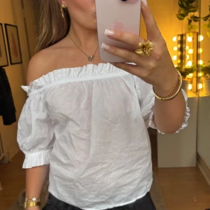 Vit offshoulder blus - Superfin vit offshoulder blus med volangkant upptill och puffiga halvlånga ärmar. Jätte fin topp i luftigt material. Läs bion innan köp. Superfin till ett par jeans eller kjol. Finns inga defekter och den är i fint skick