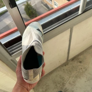  Puma fotbollsskor - Säljer ett par grymma fotbollsskor från Puma i vitt och grått med svarta detaljer och en riktigt snygg rosa sula. Skorna har strumpliknande passform och är tillverkade i syntetmaterial för bästa känsla på planen.