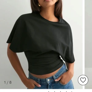 Svart croppad topp med asymmetrisk ärm - Säljer en svart croppad topp med unik asymmetrisk design och kort ärm. Toppen har en tight passform i midjan. Helt oanvänd!!💕