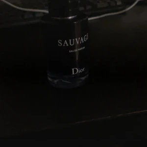 Dior Sauvage Eau de Parfum - Säljer en flaska Dior Sauvage Eau de Parfum. Flaskan är mörkblå med vit text och har en stilren, rund design. En ikonisk herrdoft med fräsch och kryddig karaktär, perfekt för dig som vill sticka ut med en modern och maskulin parfym.