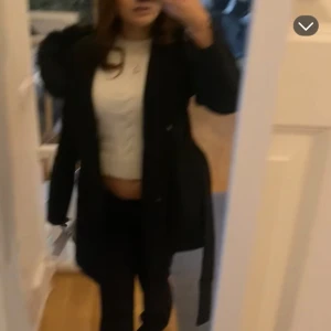 Hoolister Svart kappa med  - Säljer en svart lång kappa t matchande bälte i midjan. Jackan har en klassisk och stilren look, perfekt för dig som vill ha något snyggt och varmt till höst och vinter. Långärmad och med snygg passform. Före bikzer skickad privat 