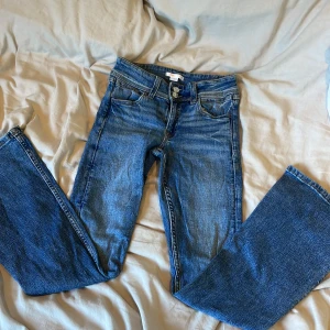 Blå jeans från Gina Tricot, stl 152 - Snygga blå jeans från Gina Tricot i klassisk modell med raka ben och normal passform. Jeansen har fem fickor, dubbla knappar i midjan och cool broderad detalj på bakfickorna. Perfekta till vardags och lätta att matcha med allt.