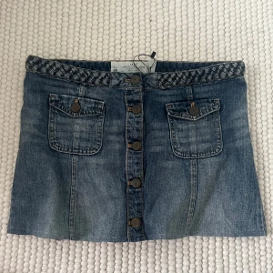 Blå jeanskjol med flätad midja  - Snygg blå jeanskjol från H&M med flätad midja och knappar hela vägen framtill. Lågmidjad och Två fickor💗 passar xs-m