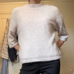 Beige stickad tröja & Other Stories - Supermjuk och fluffig beige stickad tröja från & Other Stories. Tröjan har rund halsringning och trekvartsärmar, perfekt för lager-på-lager. Enkel och stilren design som är lätt att matcha med allt.