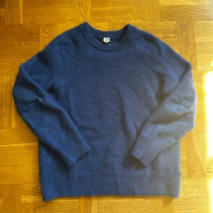 Blå stickad Arket tröja  - Mysig blå stickad Arket tröja i storlek medium med rund hals och ribbade muddar vid ärmslut och nederkant. Perfekt för dig som gillar enkel och klassisk stil. Passar dig som vill ha en skön och varm tröja till hösten eller vintern.