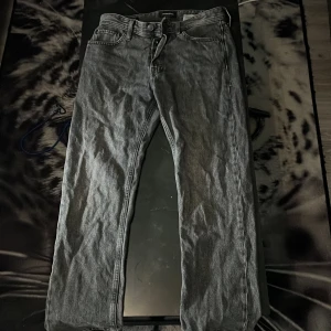Grå jeans Jack & Jones Relaxed/Chris - Säljer ett par grå jeans från Jack & Jones i modellen Relaxed/Chris. De har en avslappnad passform och klassisk femficksdesign. Jeansen är raka i benen och tillverkade i slitstarkt denimtyg. Perfekta för dig som gillar en chill och enkel stil.