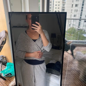 Silverglittrig omlottväst - Snygg silverfärgad väst med glittrig finish och omlottmodell. Västen har trekvartsärmar och är lätt croppad, perfekt att slänga över ett linne för en cool look. Materialet känns mjukt och stretchigt, vilket gör den bekväm att bära hela dagen.