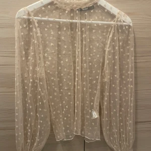 Beige meshblus med hjärtan från Bik Bok - Topp med  smockade muddar och rund halsringning. Använd någon enstaka gång