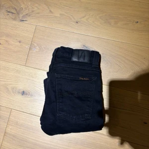 Svarta jeans från Nudie Jeans - Säljer ett par svarta jeans från Nudie Jeans.                                              Bra skick  Model: Tube Tom  Storlek: 27/34  Ny pris : 1500 kr                               Mitt pris: 299 kr