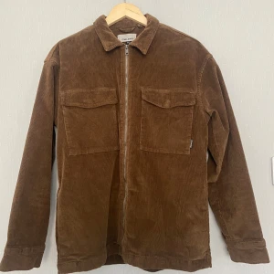 Brun manchester overshirt från Blend - Säljer en brun overshirt från Blend i mjuk manchester. Jackan har två stora bröstfickor med lock, klassisk krage och dragkedja framtill. Perfekt för lager-på-lager och ger en chill vibe till din outfit.