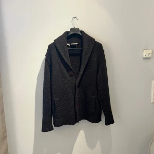 Mörkbrun kofta från Pure DKNY - Mysig mörkbrun kofta från Pure DKNY i storlek M. Tillverkad av lammull och silke, med bred krage och knappar framtill. Koftan har långa ärmar, ribbade muddar och två fickor. Perfekt för lager-på-lager under kyliga dagar. Hör av er vid frågor eller fler bilder