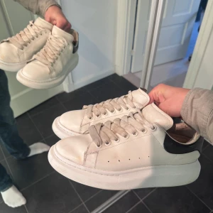 Alexander McQueen vita sneakers - Dags att sälja mina Alexander McQueen sneakers då dom aldrig används längre. Skorna har används till vardags och ger fortfarande ett väldigt gott helhetsintryck,  finns inga skador utöver ”normalt slitage”, sömmarna nedanför skosnörena har börjat släppa dock. Insidan vid hälen var sliten men har lagats hos skomakar (se sista bild). Endast skor tillkommer. Storlek 44. 