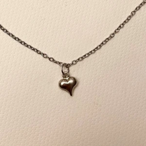 Choker Hjärta Halsband silver imitation  - Ett litet silvrigt hjärta trätt på en kortare kedja i silverimitation. Justerbar 35-40 cm. För en stilren och samtidigt gullig look!  