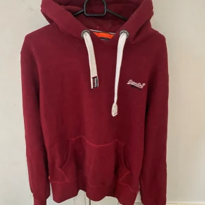 Vinröd superdry hoodie - Vinröd hoodie från Superdry i storlek S, modellen är ca 180cm. Hör av dig vid funderingar!