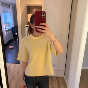 Gul stickad tröja från Gina Tricot - Superfin ljusgul stickad tröja från Gina Tricot i ullblandning. Tröjan har korta ärmar, rund halsringning och en loose fit som ger en chill vibe. Perfekt att styla med jeans eller kjol för en fräsch look. I storlek S.