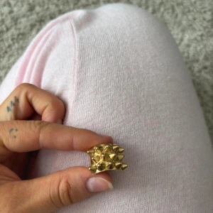 Guldfärgad Edblad ring med nitar - Cool och chunky ring från Edblad i guldfärgad metall. Ringen har ett unikt designmönster med flera konformade nitar som ger en edgy vibe. Perfekt för dig som vill sticka ut med ditt smycke och addera lite attityd till din stil.